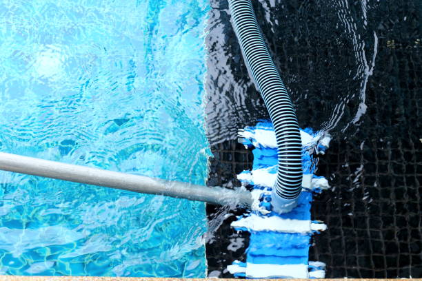 Worker clean private swimming pool with vacuum blue tube cleaner every week in Summer