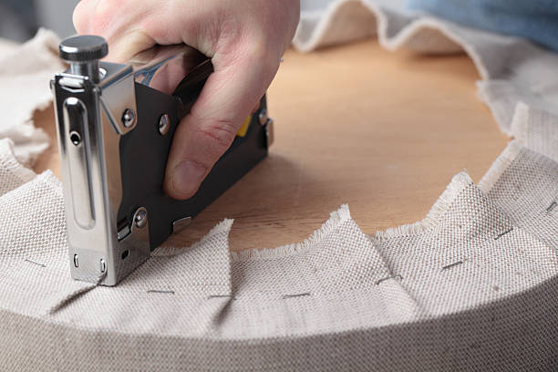 Man upholstering a round stool seat