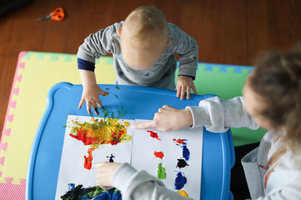 a Baby boy finger painting with his mother.